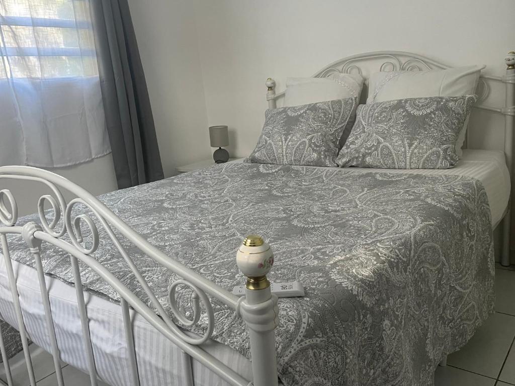 - une chambre avec un lit et une couette grise et blanche dans l'établissement location pour la famille, à Sainte-Anne