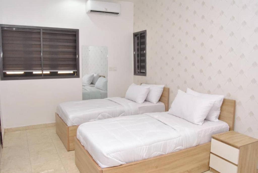 two beds in a room with white walls at Ibadan Serviced Apartments in Ibadan