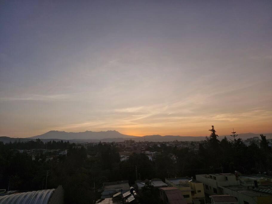 un coucher de soleil sur une ville avec des montagnes en arrière-plan dans l'établissement Departamento con Hermosa Vista, à Yanahuara