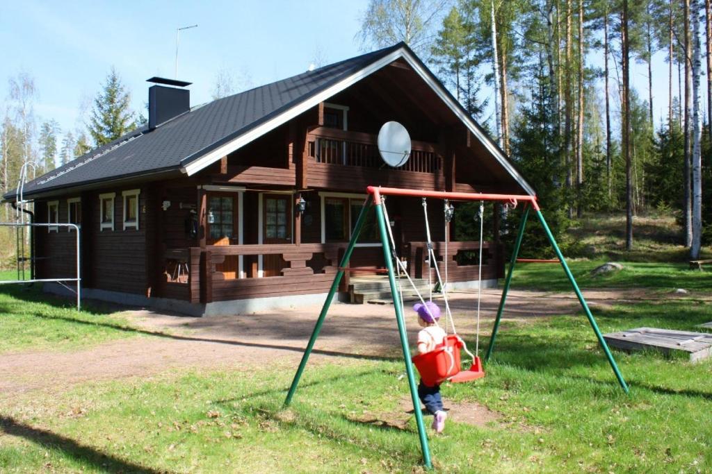 Ferienhaus in Kouvola mit Terrasse und Grill في كووفولا: طفل على مرجيحة أمام المنزل