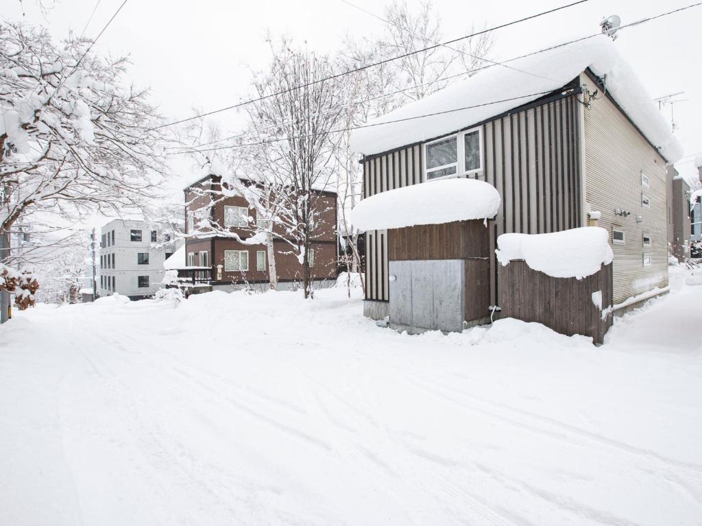 a snow covered street with houses and a house at Ajisai Chalet in Niseko