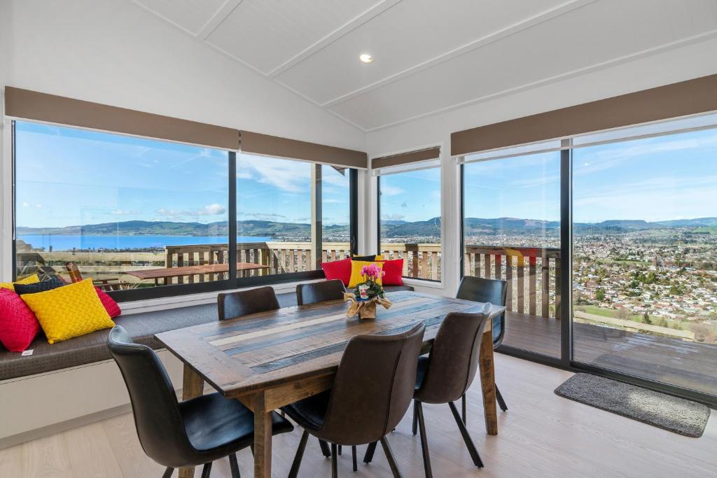 - une salle à manger avec une table, des chaises et de grandes fenêtres dans l'établissement The Lookout, à Rotorua