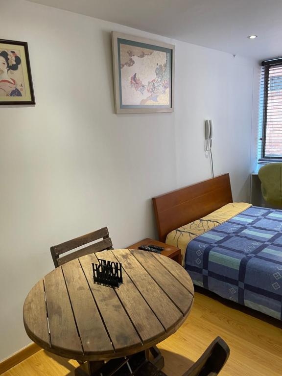 Pokój z drewnianym stołem i łóżkiem w obiekcie Apartaestudio 95 w mieście Bogota