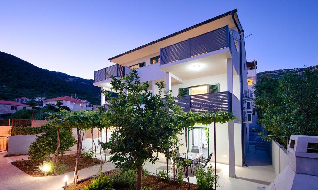 a white house with a blue door and some trees at Apartments and rooms by the sea Komiza, Vis - 9722 in Komiža