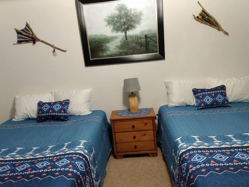 um quarto com duas camas e uma mesa com uma fotografia na parede em Mokee Motel em Lake Bluff