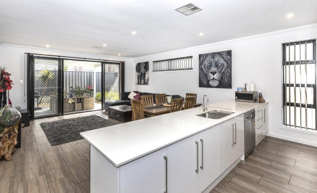 an open kitchen and living room with a lion picture on the wall at Luxury home in Christies Beach with King Bed, NBN, Netflix, 3Bed 2Bath in Christies Beach