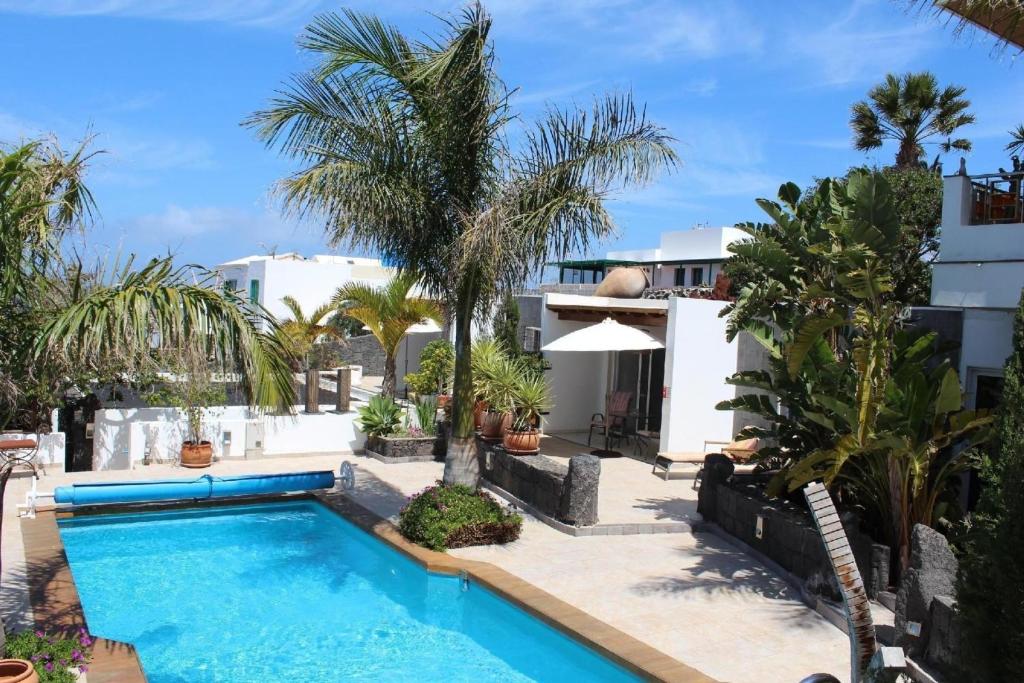 una piscina frente a una casa con palmeras en Ferienhaus aus zwei Wohneinheiten bestehend mit beheiztem Pool und Terrasse - b44101, en Playa Blanca