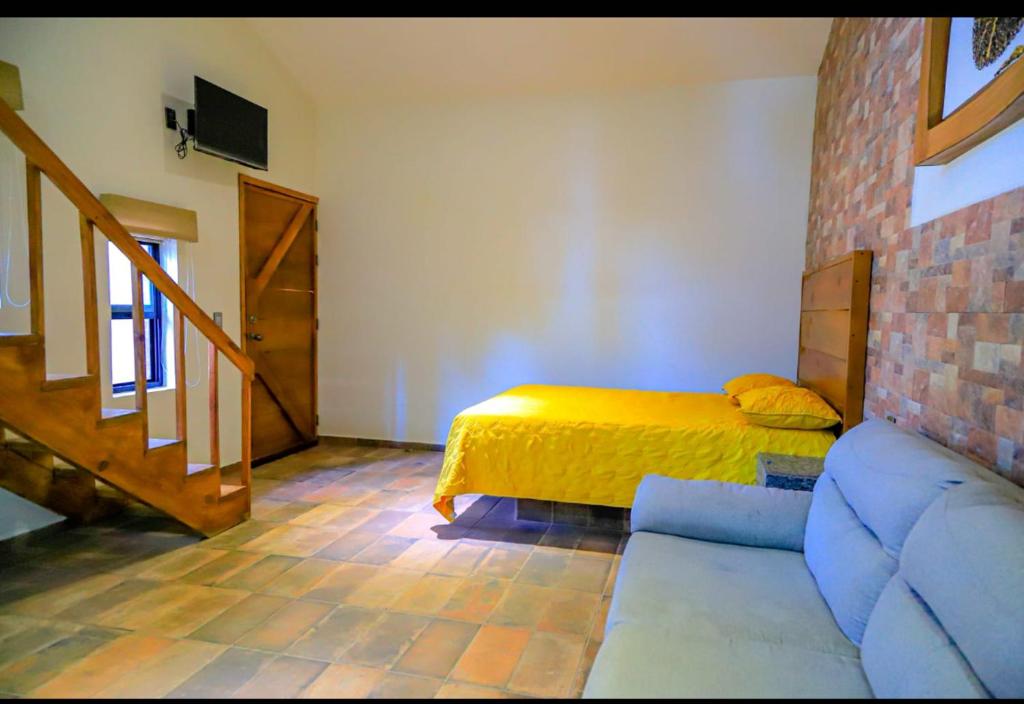 ein Schlafzimmer mit einem Bett und einem Sofa in einem Zimmer in der Unterkunft La Ocotera hotel de montaña in La Esperanza