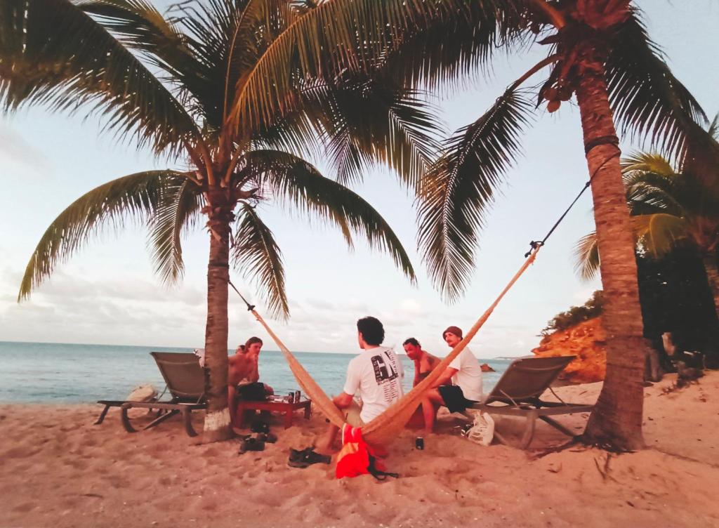 Five Islands Village的住宿－Beachfront Acqua Villa，一群人坐在海滩上的吊床上