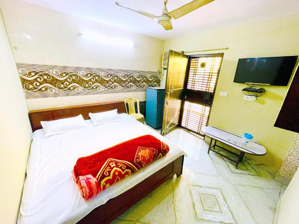 1 dormitorio con 1 cama con manta roja y TV en AMAN RESIDENCY, en Nueva Delhi