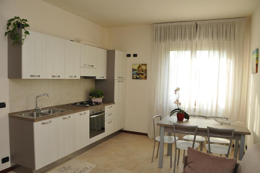 una cocina con armarios blancos y una mesa con sillas. en Appartamento Lago, en Peschiera del Garda