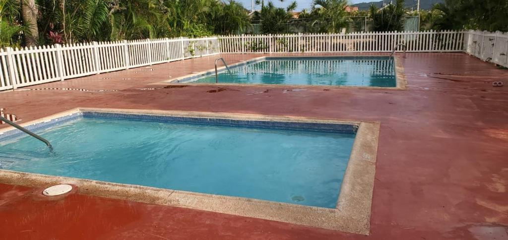 a large swimming pool with a red floor and a white fence at Finest Accommodation Caymanas House # 16 in Caymanas
