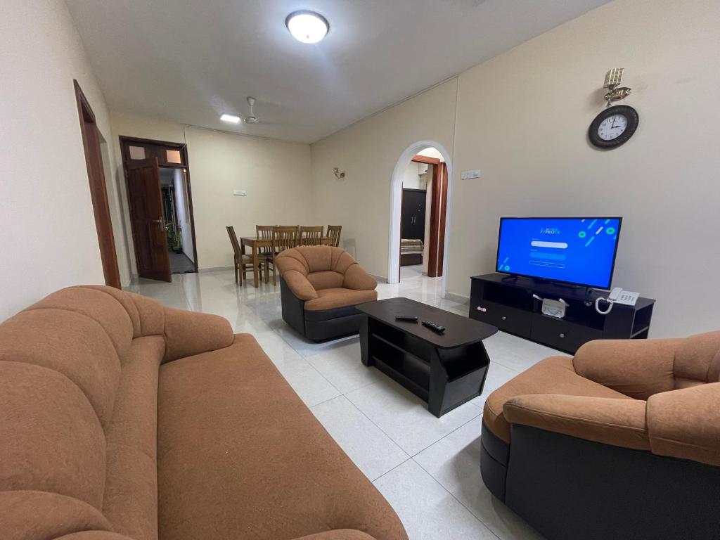 Wellawatte Apartments في كولومبو: غرفة معيشة مع كنب وتلفزيون بشاشة مسطحة