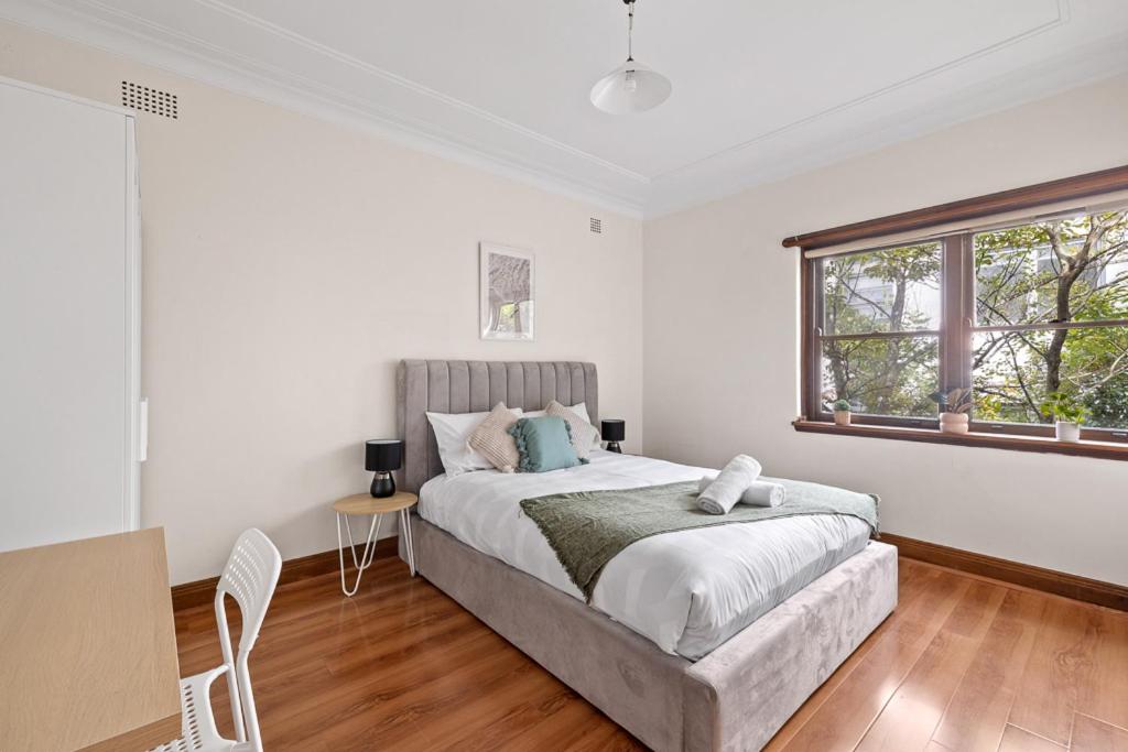 a white bedroom with a bed and a window at Cozy Lindfield Stayz in Sydney