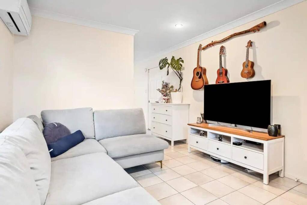 sala de estar con sofá y TV de pantalla plana en Luxurious Urban Eco Escape 3br en Brisbane