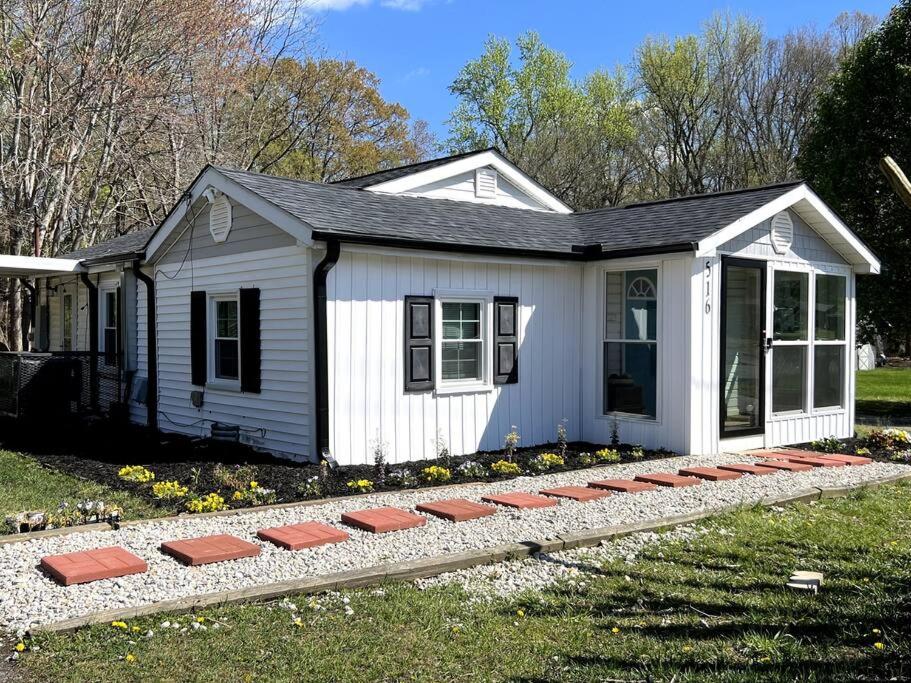 a small white house with a row of stones in front of it at Relax in Privacy in 2BR Beauty w/ Fire Pit & Grill in Greensboro