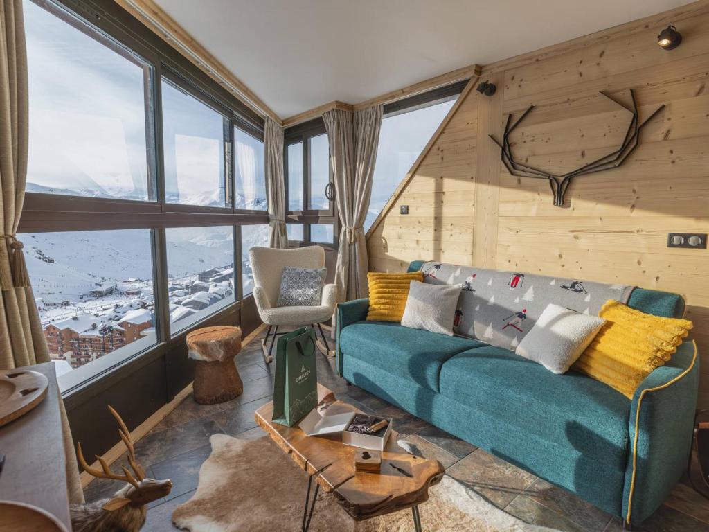 a living room with a blue couch and large windows at Appartement Val Thorens, 2 pièces, 5 personnes - FR-1-640-56 in Val Thorens