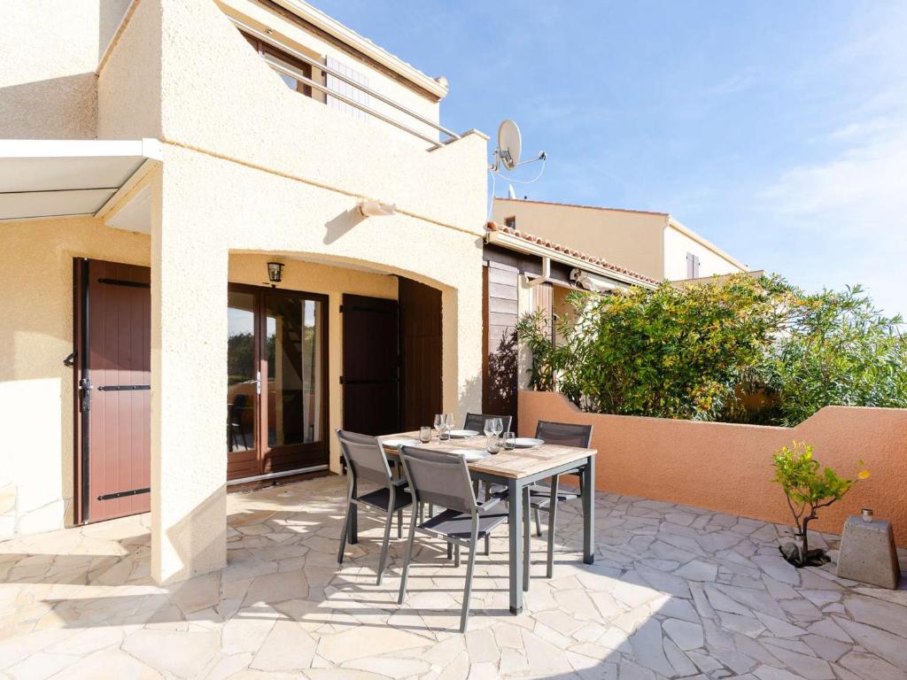 un patio avec une table et des chaises devant une maison dans l'établissement Pavillon T3 avec piscine, climatisation et parking à Narbonne-Plage - FR-1-409-248, à Narbonne
