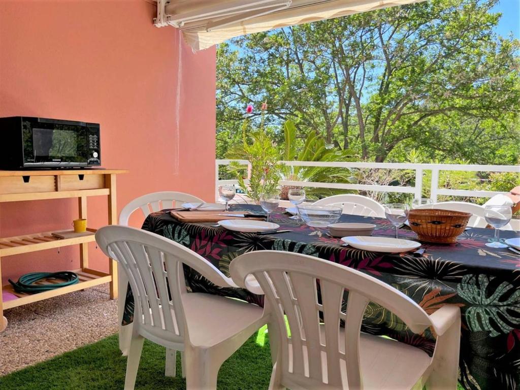 une table à manger avec des chaises blanches et une fenêtre dans l'établissement Appartement cosy à Cavalière avec terrasse, proche plage et commerces, 6 couchages - FR-1-251-546, au Lavandou