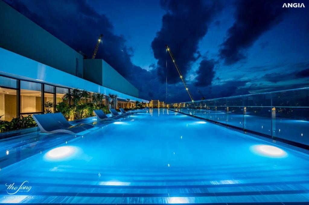 a large swimming pool with chairs and a building at Condotel The Sóng Vung Tau in Vung Tau