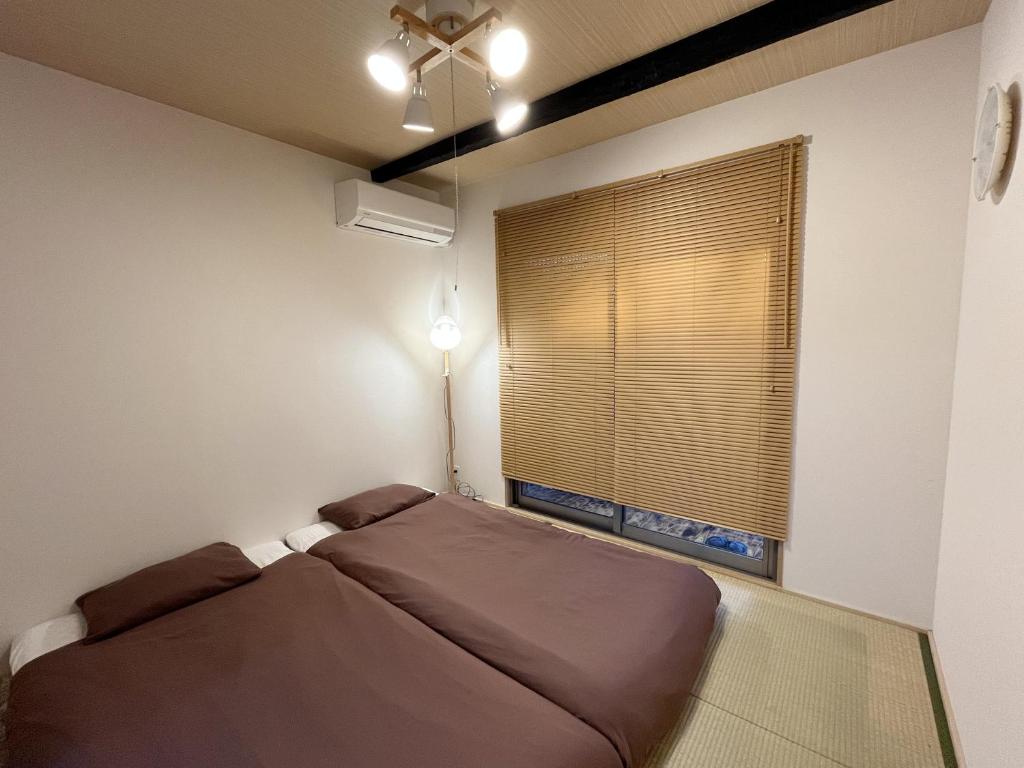 芙蓉居 日本庭園付き一戸建 【天下茶屋から徒歩8分】最大6名宿泊可能 في أوساكا: غرفة نوم صغيرة بها سرير ونافذة