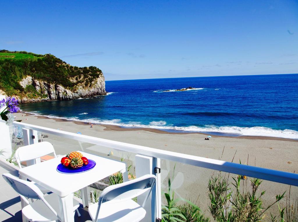 a table and chairs on a balcony overlooking the beach at Casa Da Praia in Porto Formoso