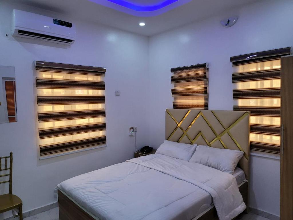 a bedroom with a bed and two windows at B&Y ROYAL BAR & LOUNGE ADIGBE ROAD ABEOKUTA in Abeokuta