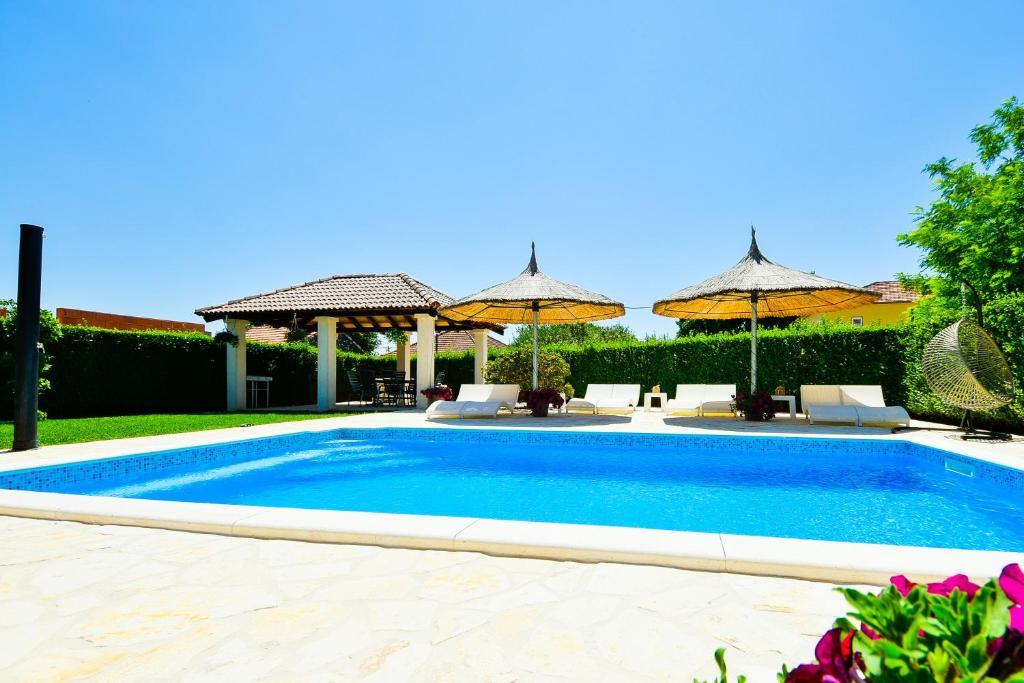 einen Pool im Garten mit Sonnenschirmen in der Unterkunft Bliss Residences Biograd Apartments - Happy Rentals in Biograd na Moru