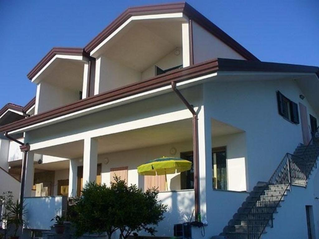 a white house with a yellow umbrella in front of it at Ferienwohnung mit Grill in gepflegter Umgebung zwischen dem See Varano Foggia und der Adria in Foce Varano