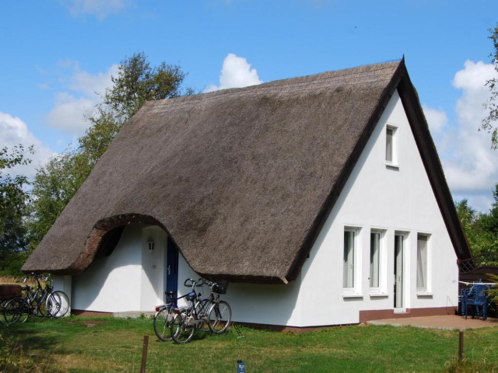 Doppelhaushälfte in Vitte auf Hiddensee في فيتيه: منزل على سقف من القش مع دراجات متوقفة في الخارج