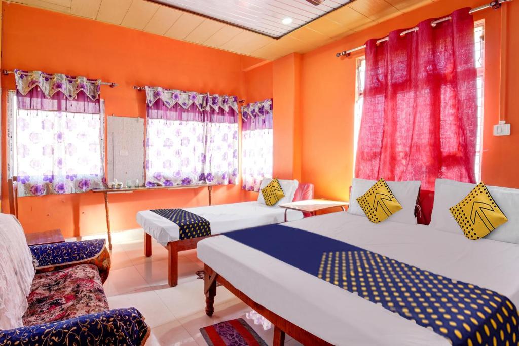 a room with two beds and a couch and windows at OYO Hotel USA Hotel in Silchar