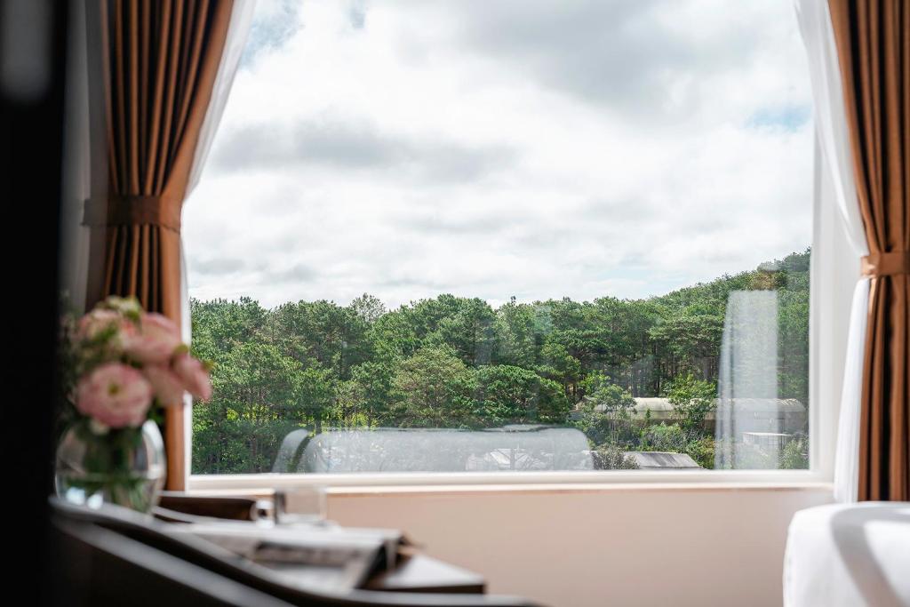 uma janela com um vaso de flores sobre uma mesa em PINE VIEW Hotel Dalat em Da Lat