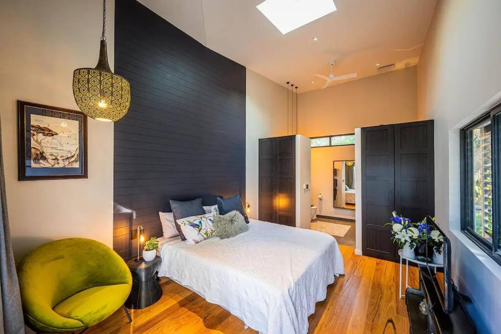 a bedroom with a bed and a green chair at Tree Top Rest - Bright Water Retreat in Bundeena