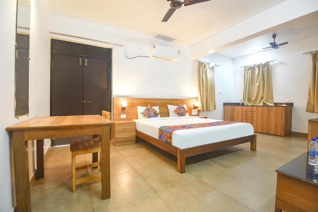 Schlafzimmer mit einem Bett, einem Tisch und einem Schreibtisch in der Unterkunft FabExpress Holiday Suites in Benaulim