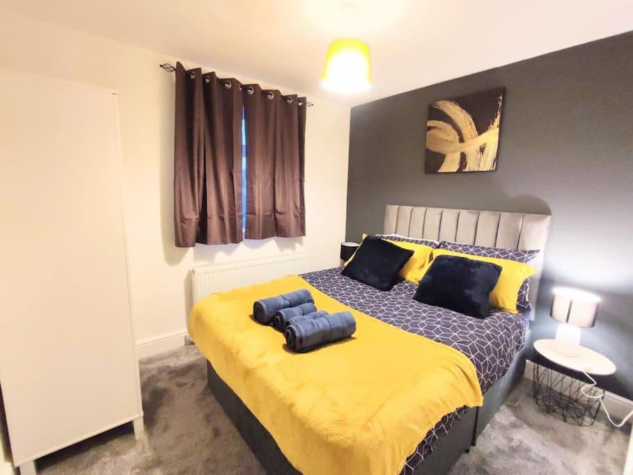 a bedroom with a large bed with yellow sheets at Sigma Lux Home in Cramlington