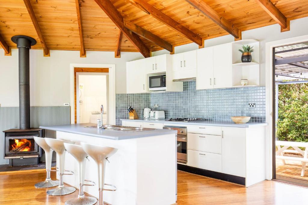 a kitchen with white cabinets and a fireplace at Hidden Orchard - Pet Friendly - 4 Mins Walk to Beach in Callala Bay