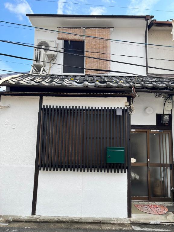 un edificio bianco con un cancello nero e una finestra di Meguli a Kyoto