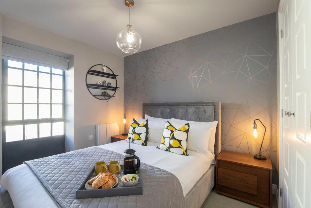 a bedroom with a bed with a tray of food on it at Elliot Oliver - Modern 2 Bedroom Town Centre Apartment in Cheltenham