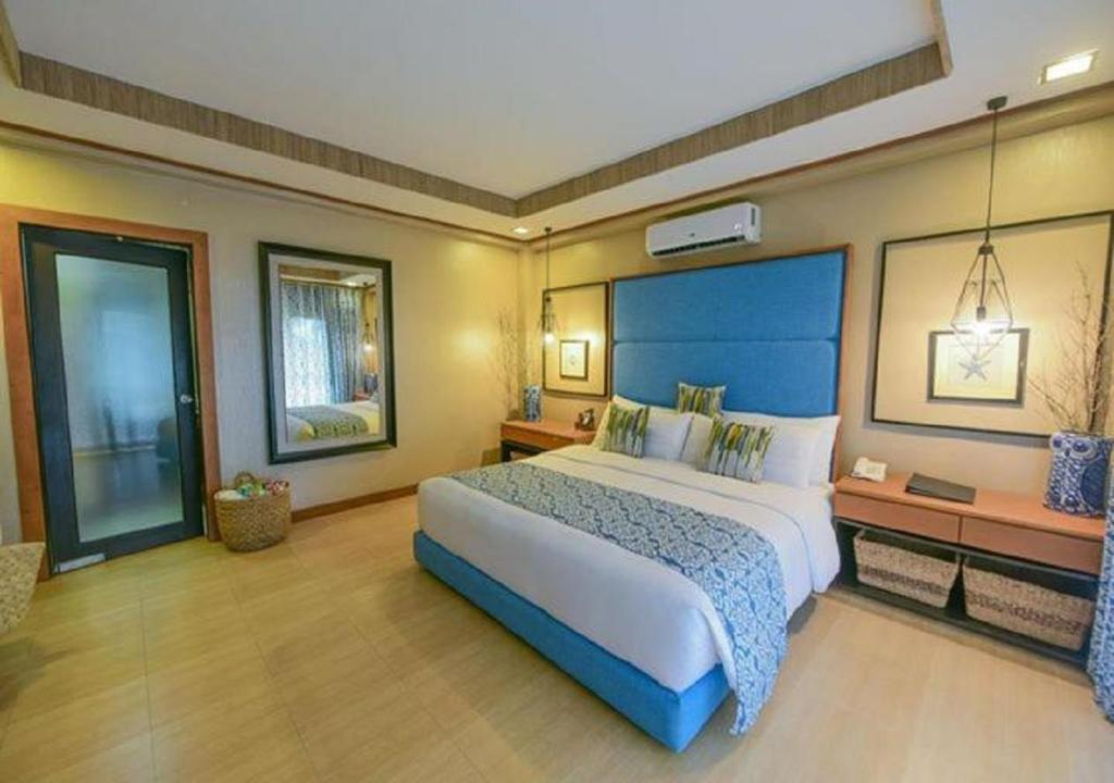 1 dormitorio grande con 1 cama grande y cabecero azul en Tugawe Cove Resort en Colongcocon