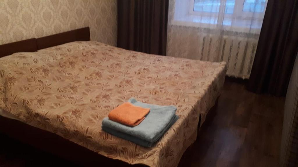 Una cama pequeña con una toalla naranja. en Кабанбай ЦГБ больница, en Semey