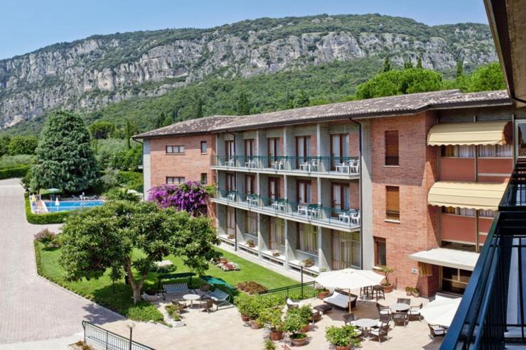 Elle offre une vue sur un hôtel avec une cour et une montagne. dans l'établissement Hotel Gabbiano - Garda Lake Collection, à Garde