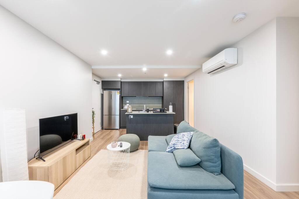 a living room with a blue couch and a television at Convenient Located 2 bedroom apartment in Braddon in Canberra