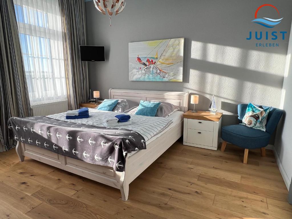een slaapkamer met een bed en een blauwe stoel bij Pension Marie Luise 252 - Zimmer Venusmuschel in Juist