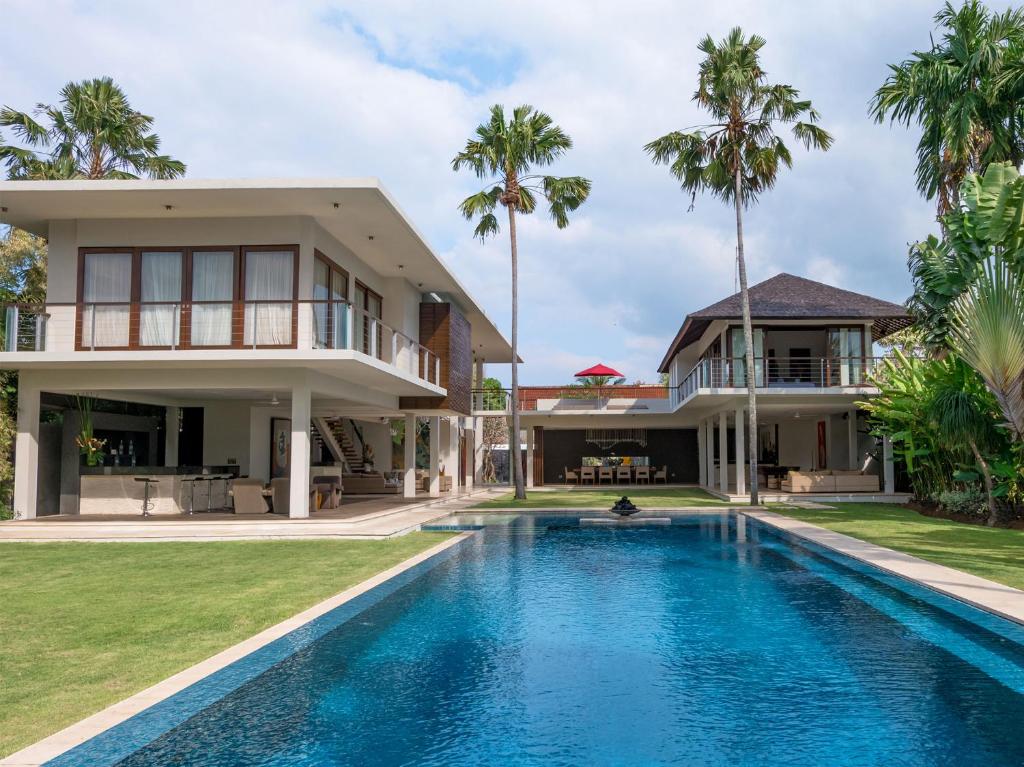 a villa with a swimming pool in front of a house at Villa Kalyani in Canggu