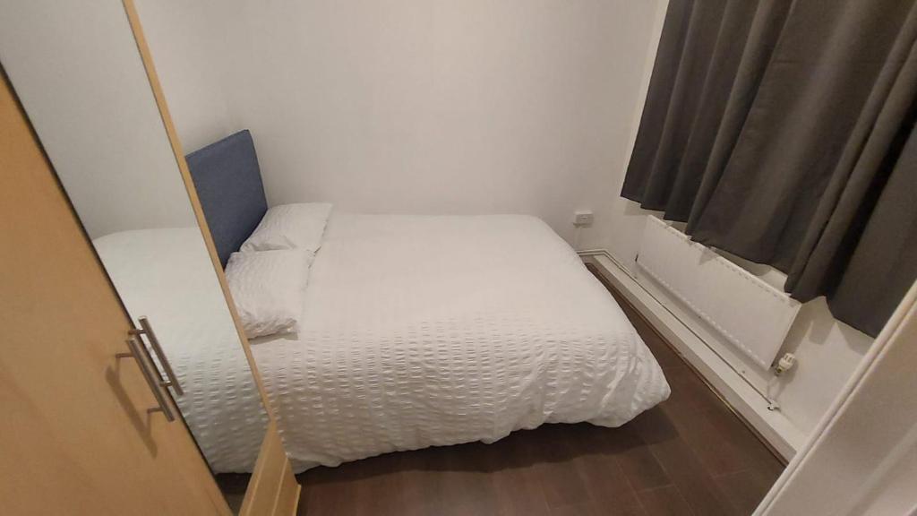 een kleine slaapkamer met een wit bed en een raam bij Bethnal Green Guest House in Londen