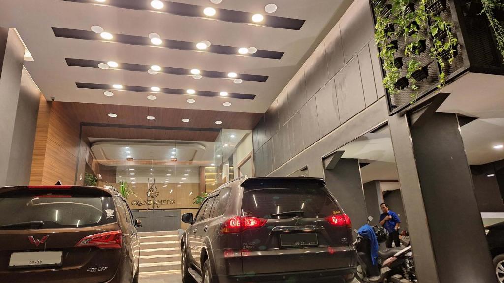 雅加達的住宿－Grand Ametis Hotel Jakarta，两辆汽车停在大楼的停车场