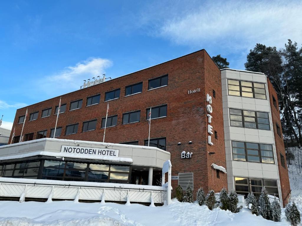 a hotel building with snow in front of it at Notodden Hotel in Notodden