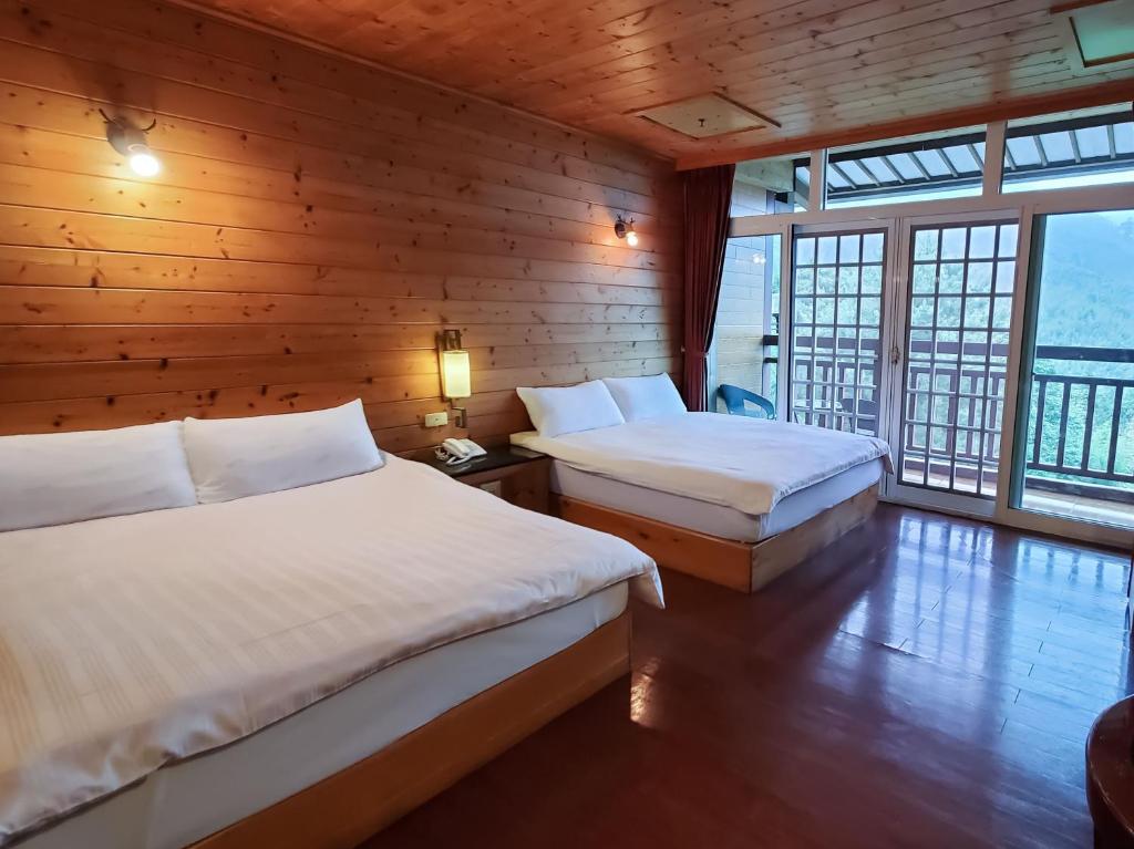 two beds in a room with wooden walls and windows at Kingtaiwan Hotel in Lugu Lake