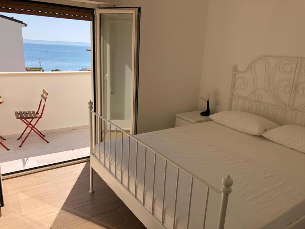 1 dormitorio con 1 cama y balcón con vistas al océano en RS304 - Marcelli, nuovo bilo fronte mare con spiaggia inclusa, en Marcelli