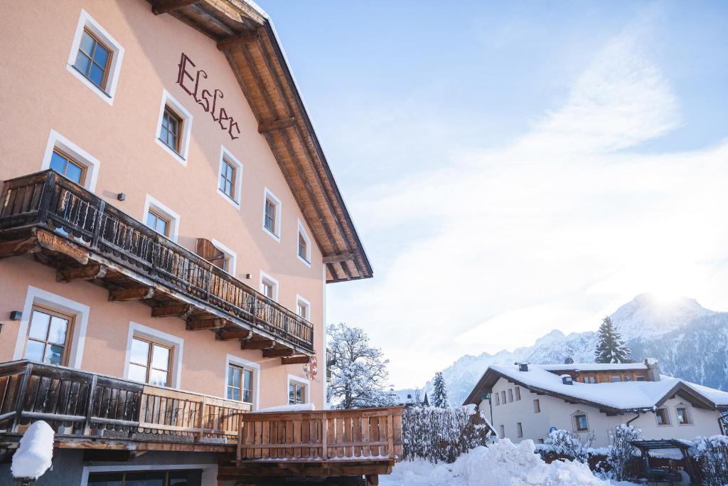 a hotel with snow on the ground next to a building at Elslerhof in Dobbiaco